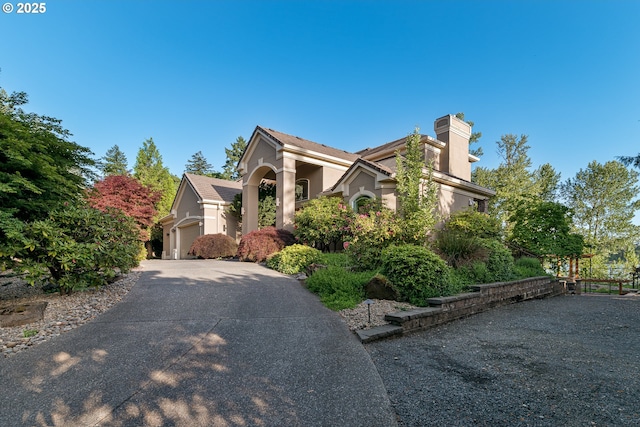 16215 SE Rivershore Dr, Vancouver, WA 98683 - view of front facade featuring stucco siding, driveway, and a chimney