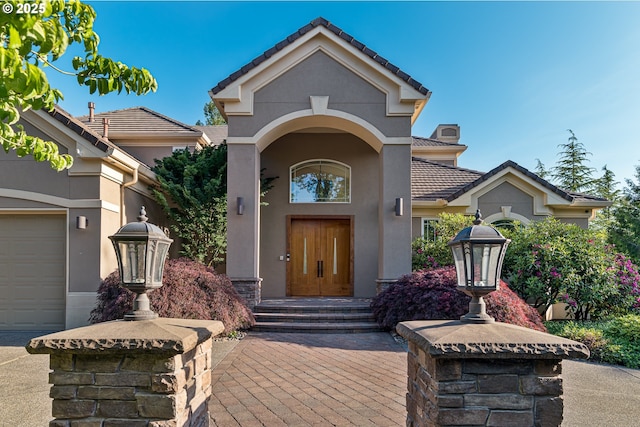 16215 SE Rivershore Dr, Vancouver, WA 98683 - view of exterior entry with a tiled roof, stucco siding, and a chimney