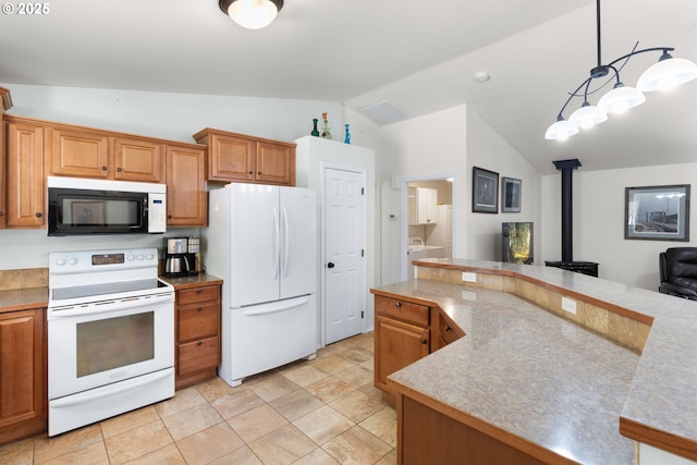kitchen featuring white appliances, a wood stove, lofted ceiling, hanging light fixtures, and brown cabinetry