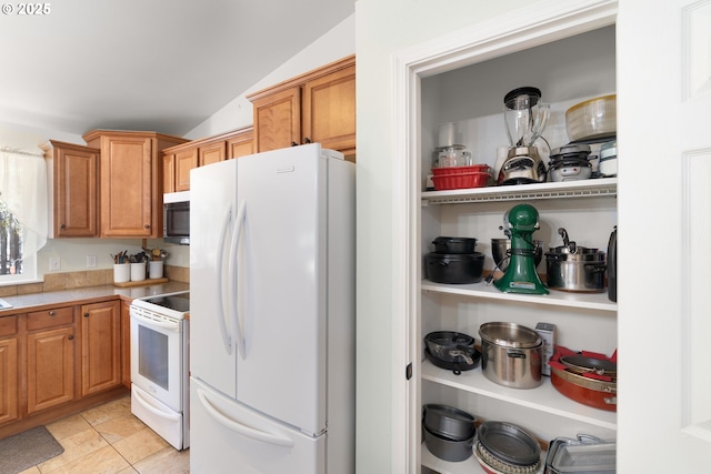 kitchen with white appliances, light countertops, vaulted ceiling, and brown cabinets