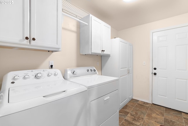 laundry room with washer and clothes dryer, cabinet space, dark stone finish floors, and baseboards
