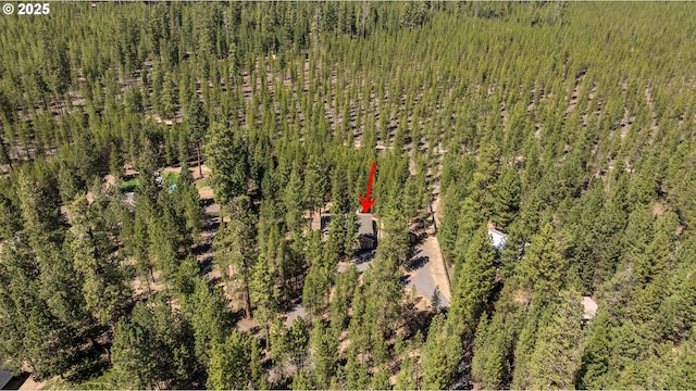aerial view of property and surrounding area featuring a heavily wooded area
