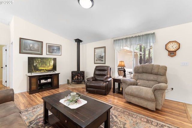 living room with a wood stove, wood finished floors, lofted ceiling, and baseboards