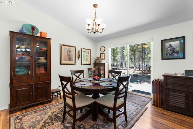 dining space with lofted ceiling, a chandelier, and wood finished floors