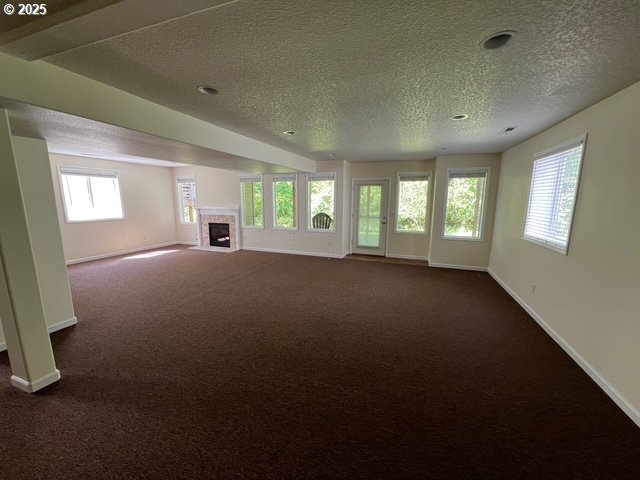 2217 NE 179th St Unit 22, Ridgefield, WA 98642 - unfurnished living room with a textured ceiling, baseboards, and dark colored carpet