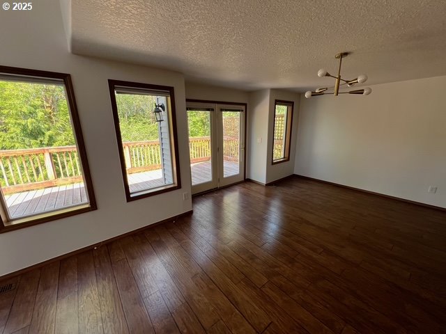 2217 NE 179th St Unit 22, Ridgefield, WA 98642 - spare room featuring dark wood-style flooring, an inviting chandelier, a textured ceiling, french doors, and baseboards