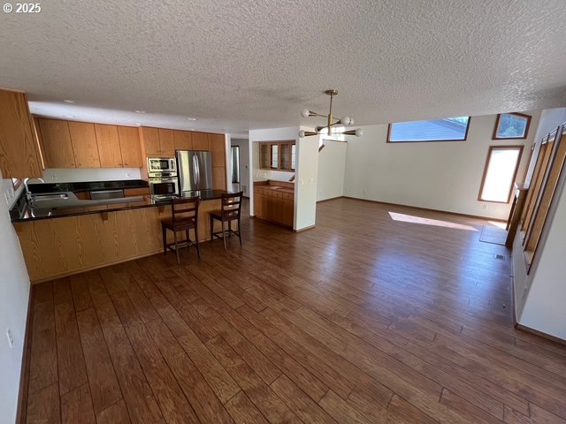 2217 NE 179th St Unit 22, Ridgefield, WA 98642 - kitchen with dark wood finished floors, stainless steel appliances, a peninsula, and a textured ceiling