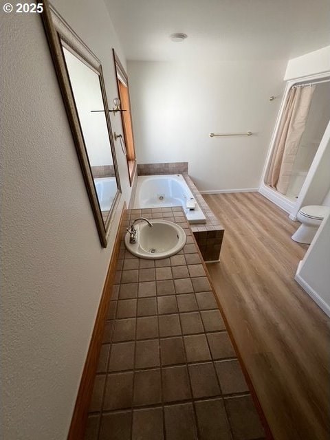 2217 NE 179th St Unit 22, Ridgefield, WA 98642 - bathroom with wood finished floors, baseboards, a shower with shower curtain, a bath, and a sink