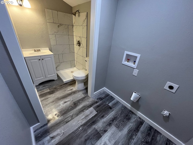 441 NE Johnson St, Myrtle Creek, OR 97457 - bathroom with toilet, wood finished floors, a stall shower, vanity, and a textured wall