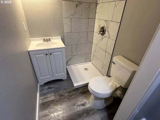 441 NE Johnson St, Myrtle Creek, OR 97457 - bathroom with a textured wall, toilet, wood finished floors, a stall shower, and vanity