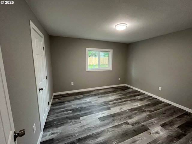 441 NE Johnson St, Myrtle Creek, OR 97457 - unfurnished bedroom with dark wood-style flooring, baseboards, and a textured ceiling