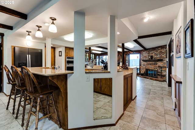 36910 Edgehill Rd, Springfield, OR 97478 - kitchen with beamed ceiling, stainless steel appliances, a fireplace, a breakfast bar, and light stone countertops