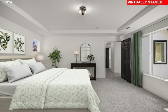 bedroom with a tray ceiling, light colored carpet, baseboards, and visible vents