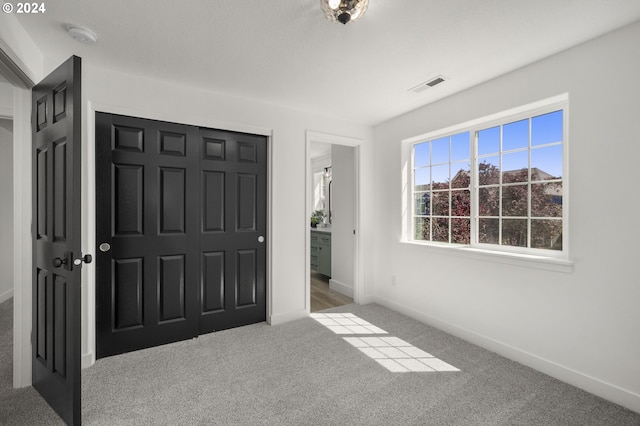 unfurnished bedroom featuring visible vents, carpet floors, baseboards, and a closet