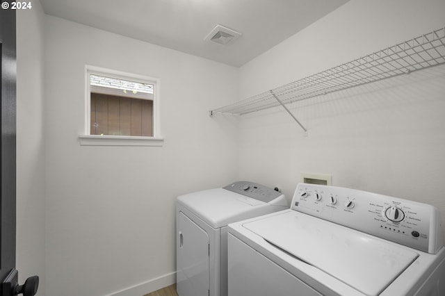 laundry room with laundry area, washing machine and dryer, visible vents, and baseboards