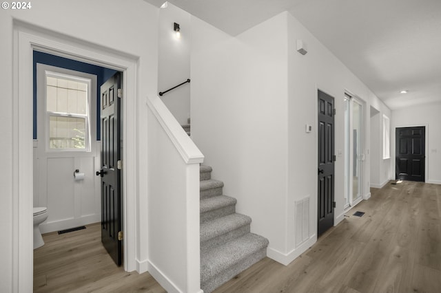 stairway with visible vents, baseboards, and wood finished floors