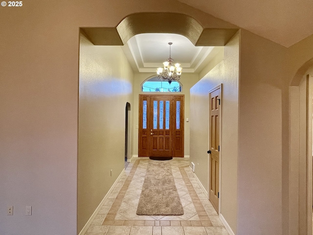 2180 Hayes St, North Bend, OR 97459 - foyer featuring arched walkways, a tray ceiling, inlaid floor details, a chandelier, and baseboards