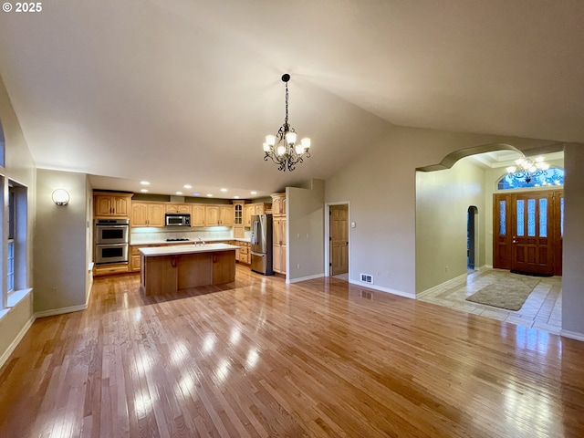 kitchen featuring light wood-type flooring, stainless steel appliances, a notable chandelier, and open floor plan