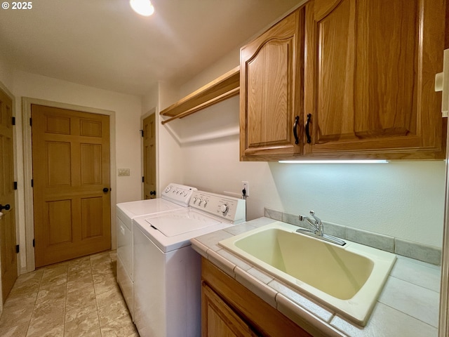 clothes washing area with washer and dryer, cabinet space, and a sink