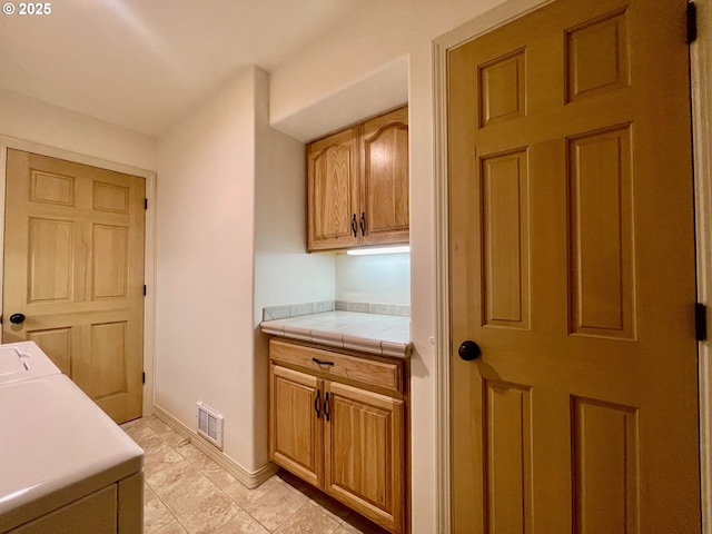 washroom with visible vents, cabinet space, and baseboards