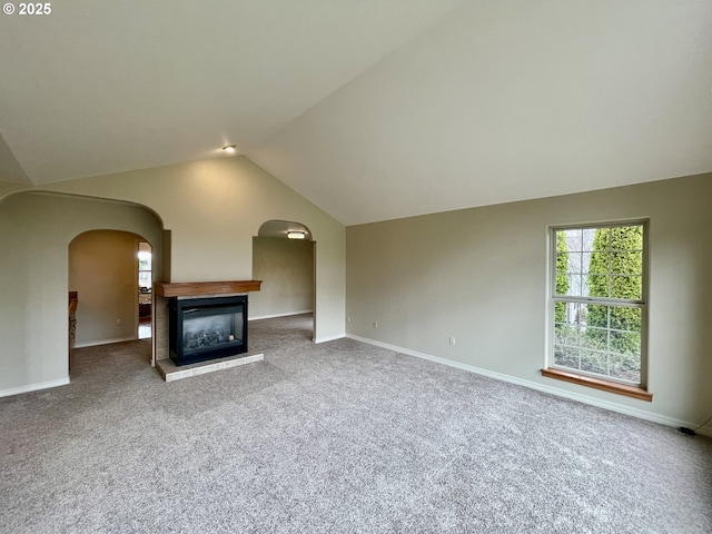 unfurnished living room with baseboards, a multi sided fireplace, lofted ceiling, and a healthy amount of sunlight