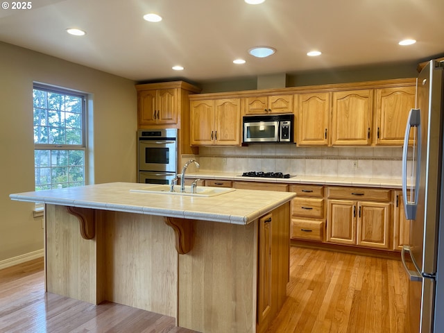 2180 Hayes St, North Bend, OR 97459 - kitchen featuring stainless steel appliances, a breakfast bar area, light wood-type flooring, tasteful backsplash, and tile counters
