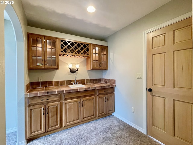 bar featuring indoor wet bar, light carpet, baseboards, and a sink