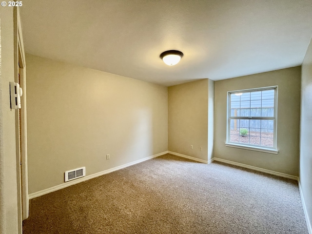 carpeted empty room featuring baseboards and visible vents