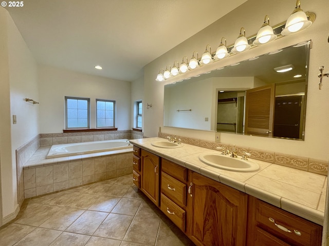 full bath featuring a sink, a bath, double vanity, and tile patterned flooring