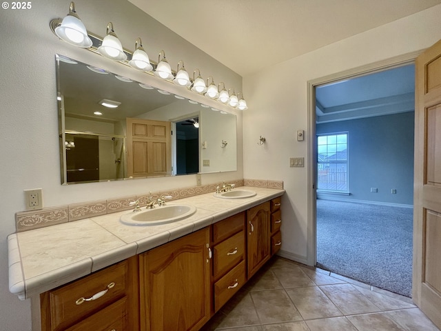 bathroom with double vanity, tile patterned flooring, a shower with shower door, and a sink