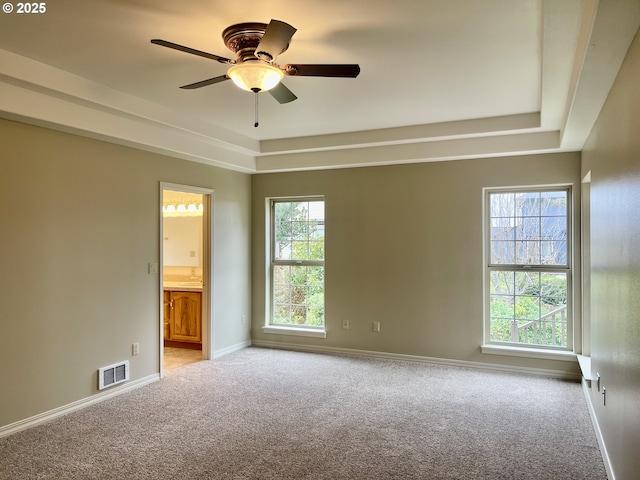 unfurnished room with visible vents, baseboards, ceiling fan, light colored carpet, and a raised ceiling