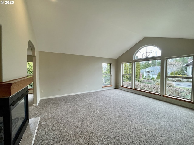 2180 Hayes St, North Bend, OR 97459 - unfurnished living room with carpet floors, a glass covered fireplace, baseboards, arched walkways, and high vaulted ceiling