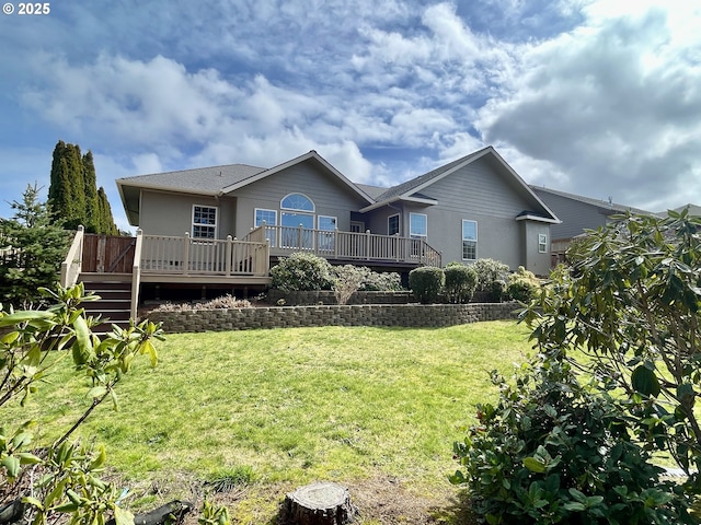 back of property with a deck, a yard, and stucco siding