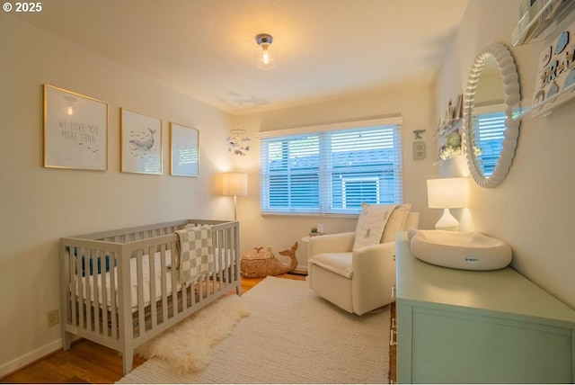 bedroom with a crib and hardwood / wood-style flooring