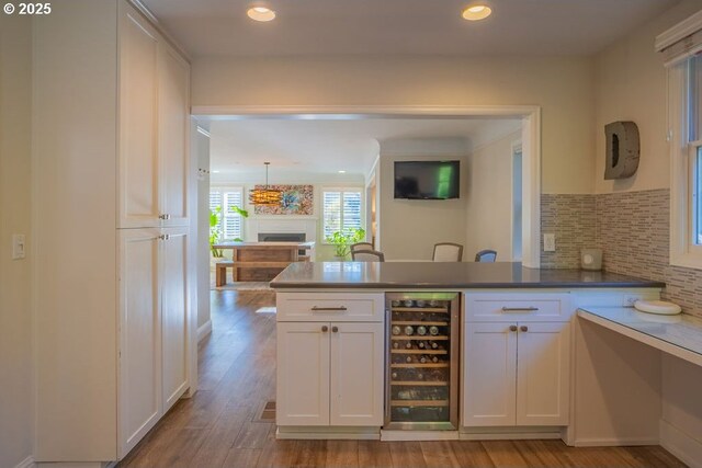 kitchen featuring white cabinets, wine cooler, decorative backsplash, kitchen peninsula, and light hardwood / wood-style flooring