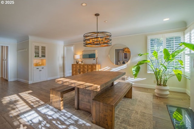 dining area with dark wood-type flooring, ornamental molding, and a chandelier