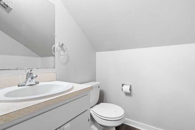 bathroom with hardwood / wood-style flooring, vaulted ceiling, vanity, and toilet