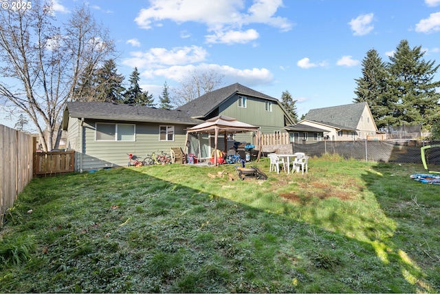 back of house with a gazebo, a yard, and a fire pit