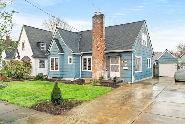 view of front of house featuring a garage, an outbuilding, and a front lawn