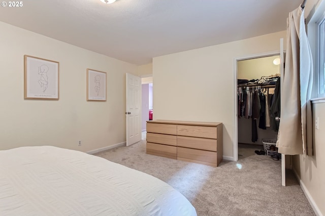 bedroom with light carpet, a walk in closet, baseboards, and a closet