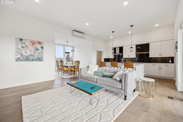 living area with light wood-style flooring, baseboards, an AC wall unit, and recessed lighting