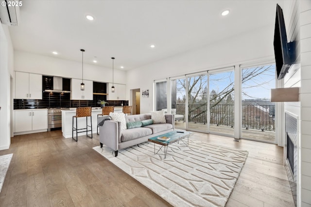 living room featuring recessed lighting, a fireplace, and light wood-style floors