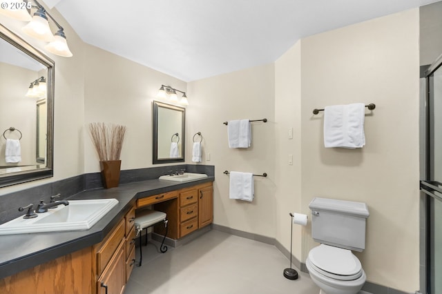 bathroom featuring toilet, double vanity, and baseboards