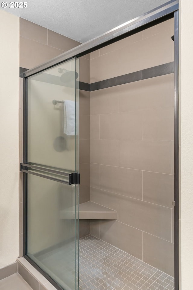 full bath featuring a shower stall and a textured ceiling