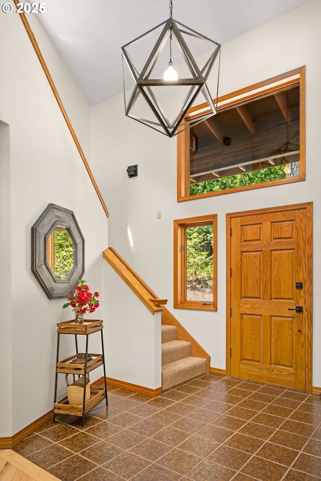 entrance foyer featuring stairs, baseboards, and a towering ceiling