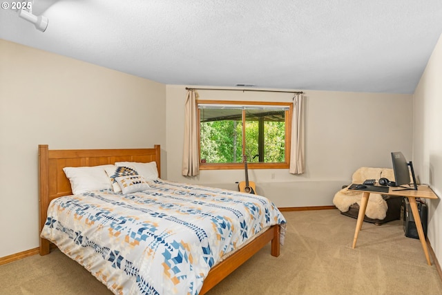 bedroom featuring light carpet, baseboards, and a textured ceiling