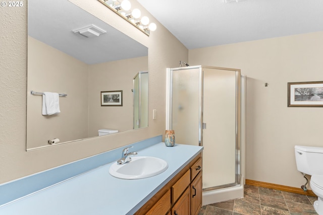 bathroom with toilet, a shower stall, baseboards, vanity, and stone finish floors