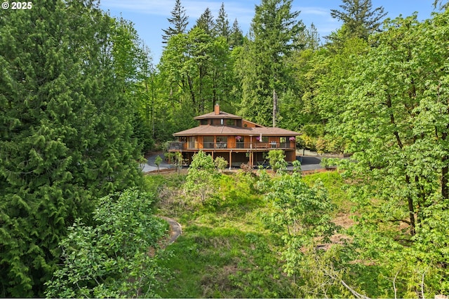 back of property with a wooden deck and a view of trees