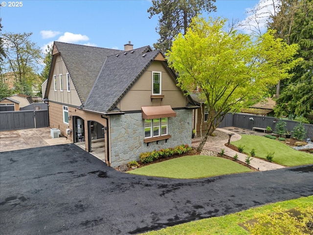 5610 NE Going St, Portland, OR 97218 - view of side of home featuring stone siding, a gate, a chimney, roof with shingles, and central AC unit
