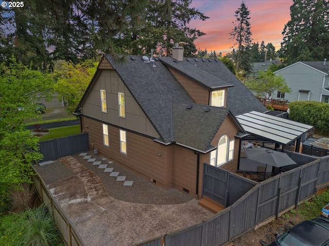 5610 NE Going St, Portland, OR 97218 - back of house at dusk with roof with shingles, a fenced backyard, a chimney, and crawl space